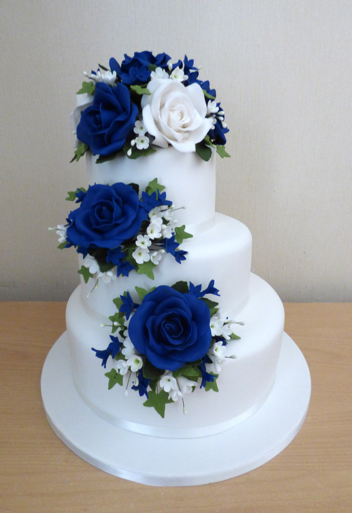 Premium Photo | A three tiered cake with blue roses on top.